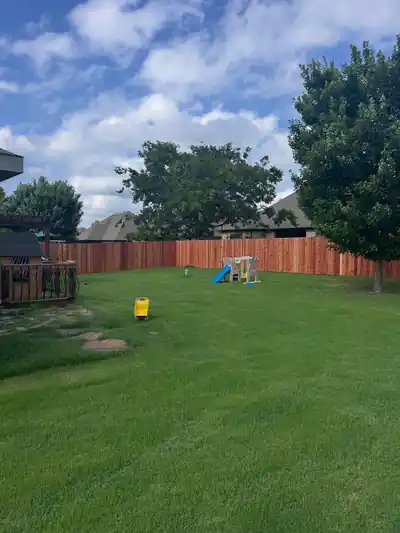 Cedar privacy fence across a large backyard with a play set