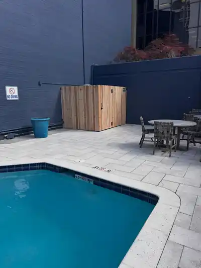 Commercial pool deck with the cedar equipment enclosure in the back corner and a No Diving sign