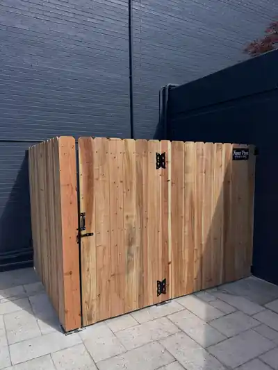 Cedar equipment enclosure with a hinged gate on a commercial pool deck against a navy wall