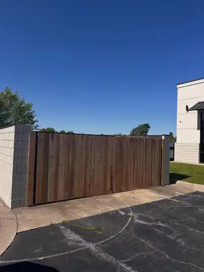 Dark-stained wood privacy fence closing off a commercial lot beside a building