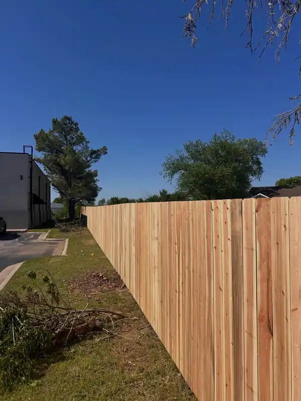 A long new cedar privacy fence run by Fence Pros NWA under a clear sky