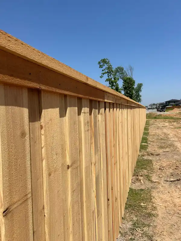 Low view down a new cedar board-on-board privacy fence with a cap and trim rail