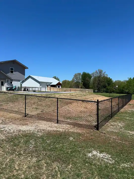 Black chain link fence enclosing a large yard and pool, installed by Fence Pros NWA