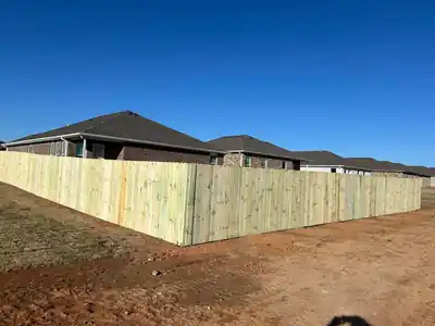 Long pine privacy fence run behind a row of new brick houses