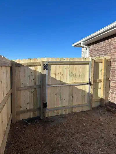 Pine fence with a steel-framed walk gate against a brick house