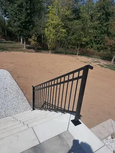Black aluminum railing running down concrete steps, seen from above