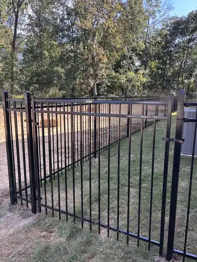 Black aluminum double gate and fence across a sloping lawn