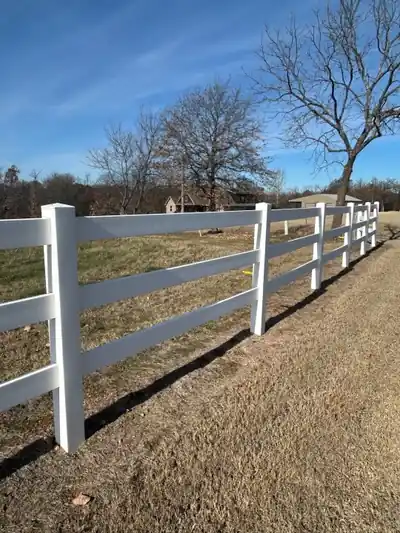 White vinyl three-rail fence along a field edge