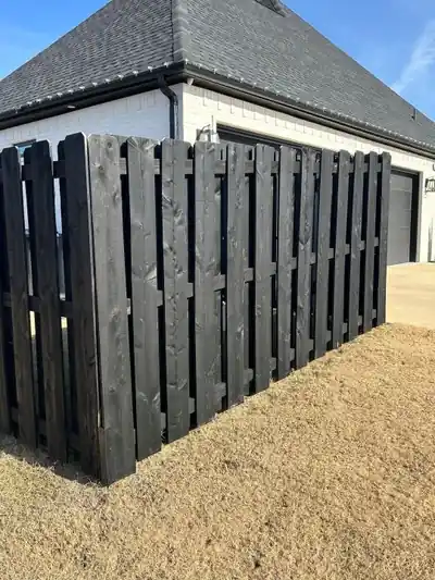 Black-stained shadowbox fence beside a white brick garage